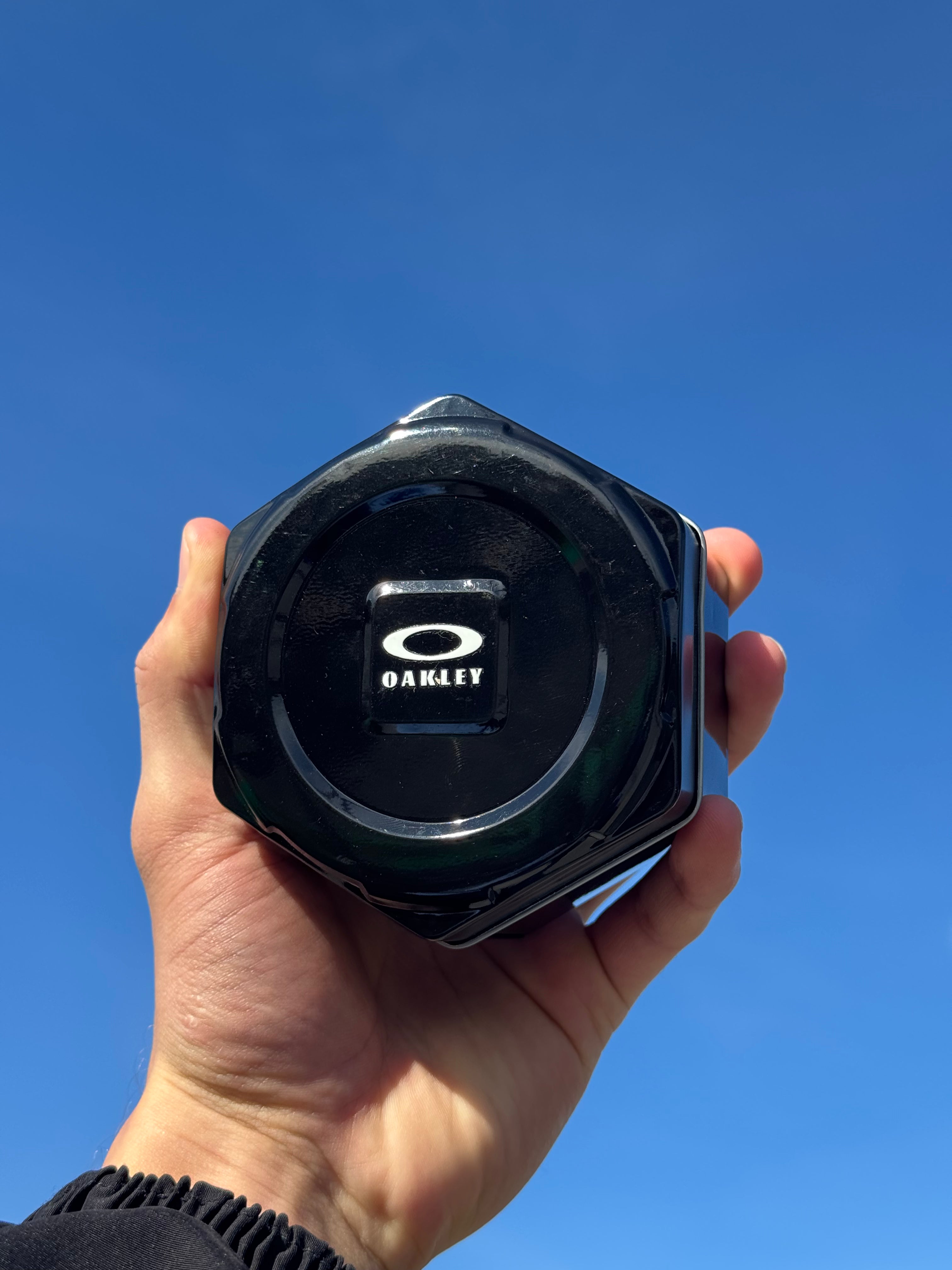 Hand holding a black watch case to sky