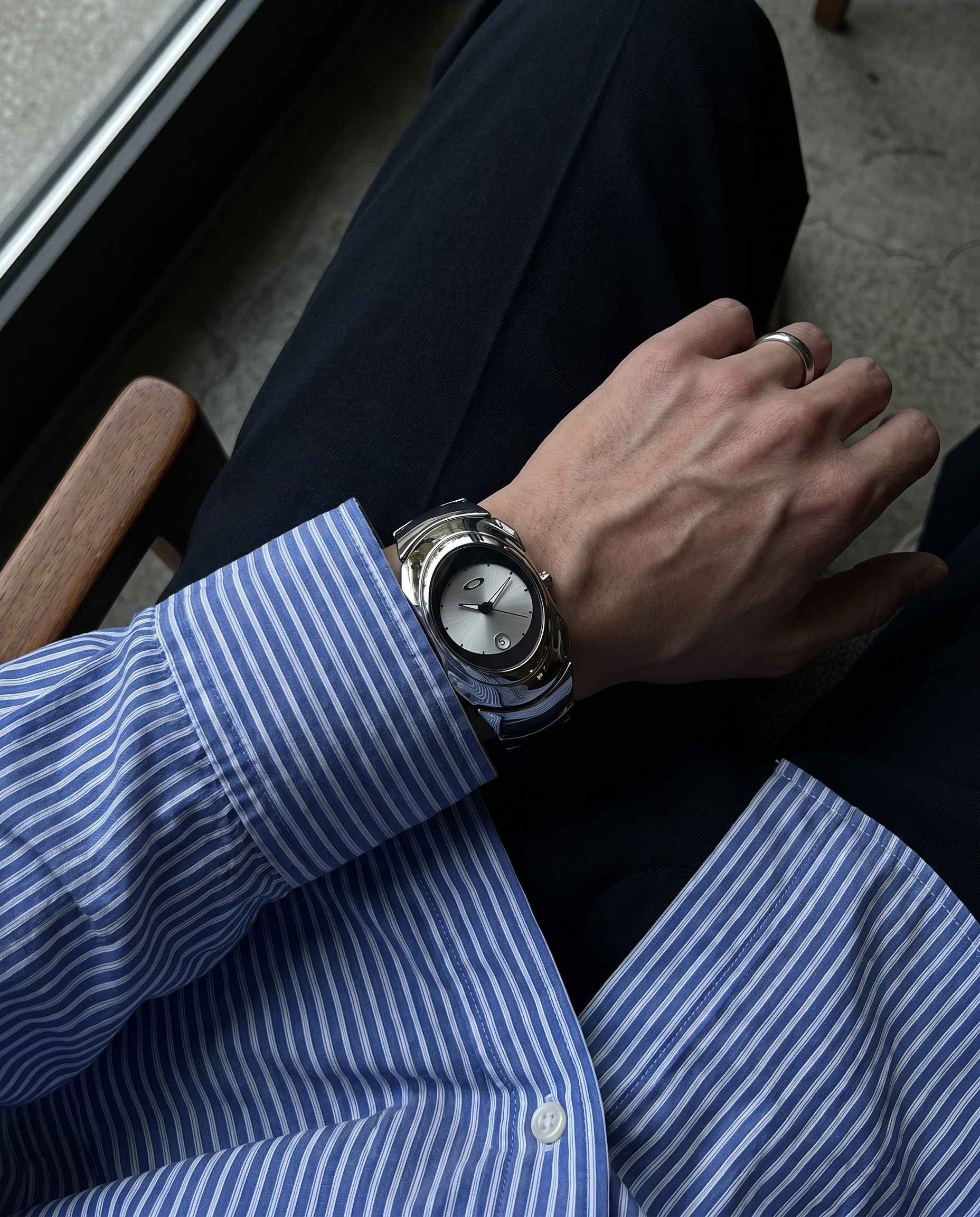 Glossy chrome Y2K watch worn under blue pinstripe shirt cuff, Aerostore Glossy Ice White showing Frutiger Aero polished stainless steel cool tones against business shirt fabric
