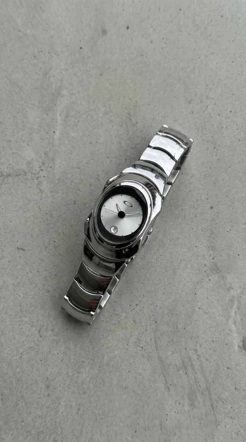 Chrome and white Y2K, 2000s steel metal watch on a clean grey concrete surface